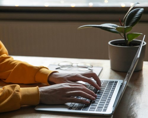 A person typing on a laptop computer on a desk